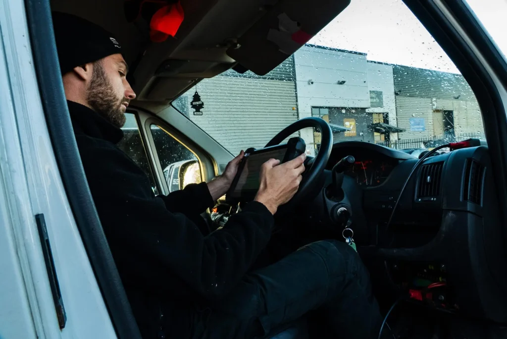 Technician working from a laptop in the driver's seat of a van